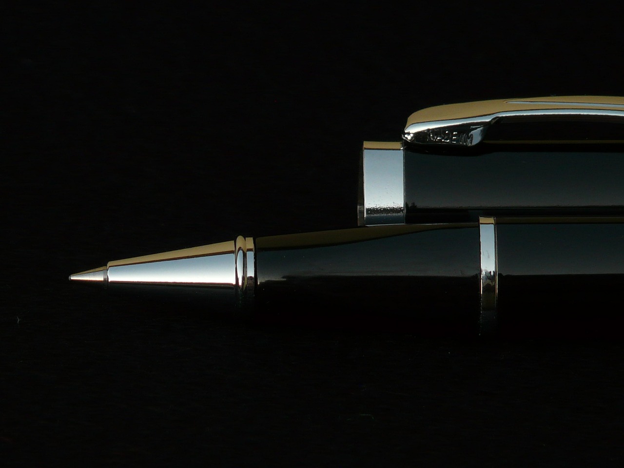 Pen emerging from darkness, lit edge only
