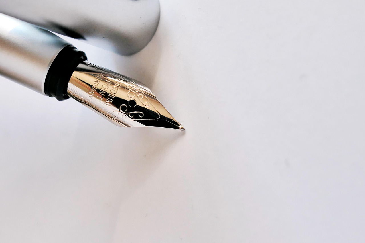 Fountain pen nib poised over white paper